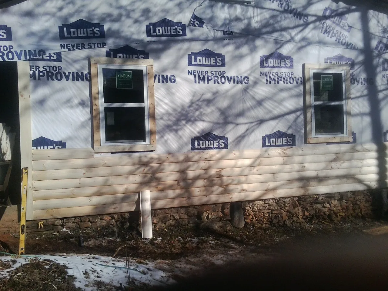 House wrap and new log siding going up on an exterior wall in Cumming