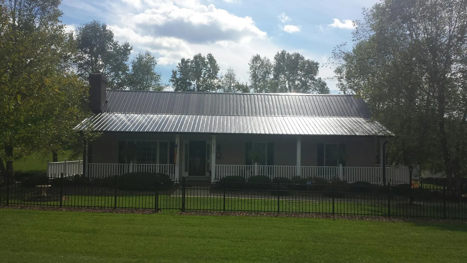 Gray metal roof on a brick ranch with a full width front porch — Gutter Guard Installation work by our crew in Cumming